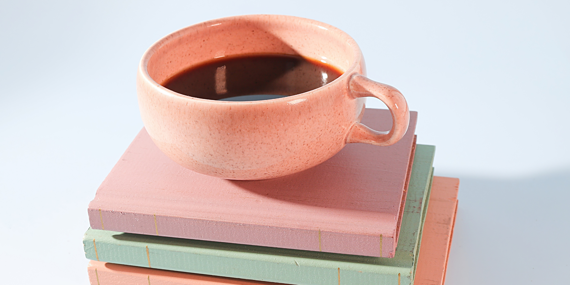 Coffee cup sitting on top of a stack of books.
